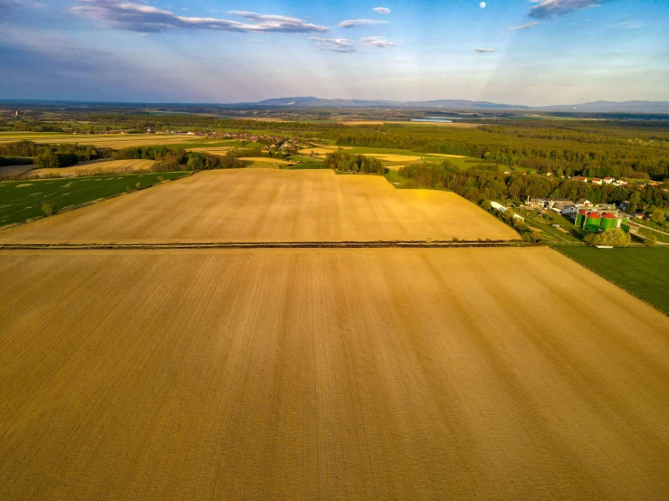 an aerial view of farm land with fields and a blue sky in the background