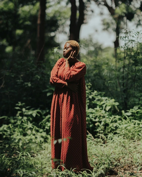 a woman in red standing in a forest