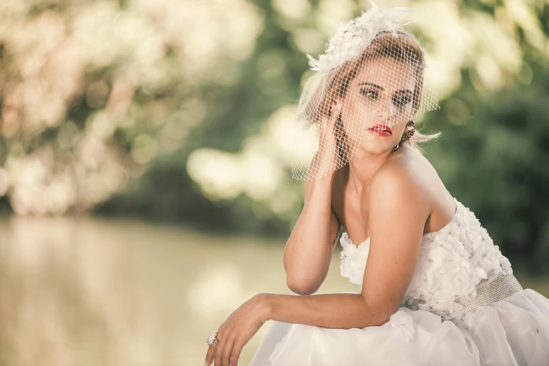 a woman in white is sitting on the ground with her hair blowing up