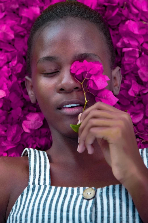 woman smiling while smelling a purple flower on her nose