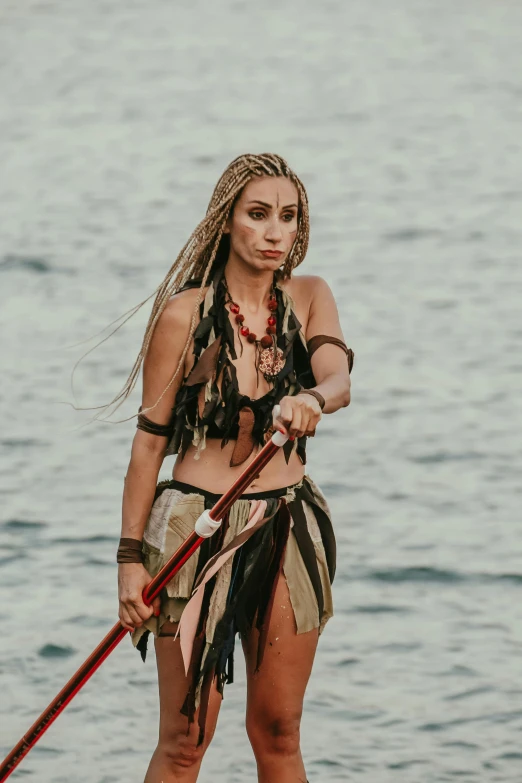 a woman with brown hair and a black outfit holding two oars on top of a body of water