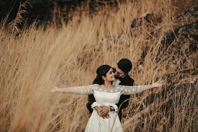 a newlywed couple in tall grass hugging