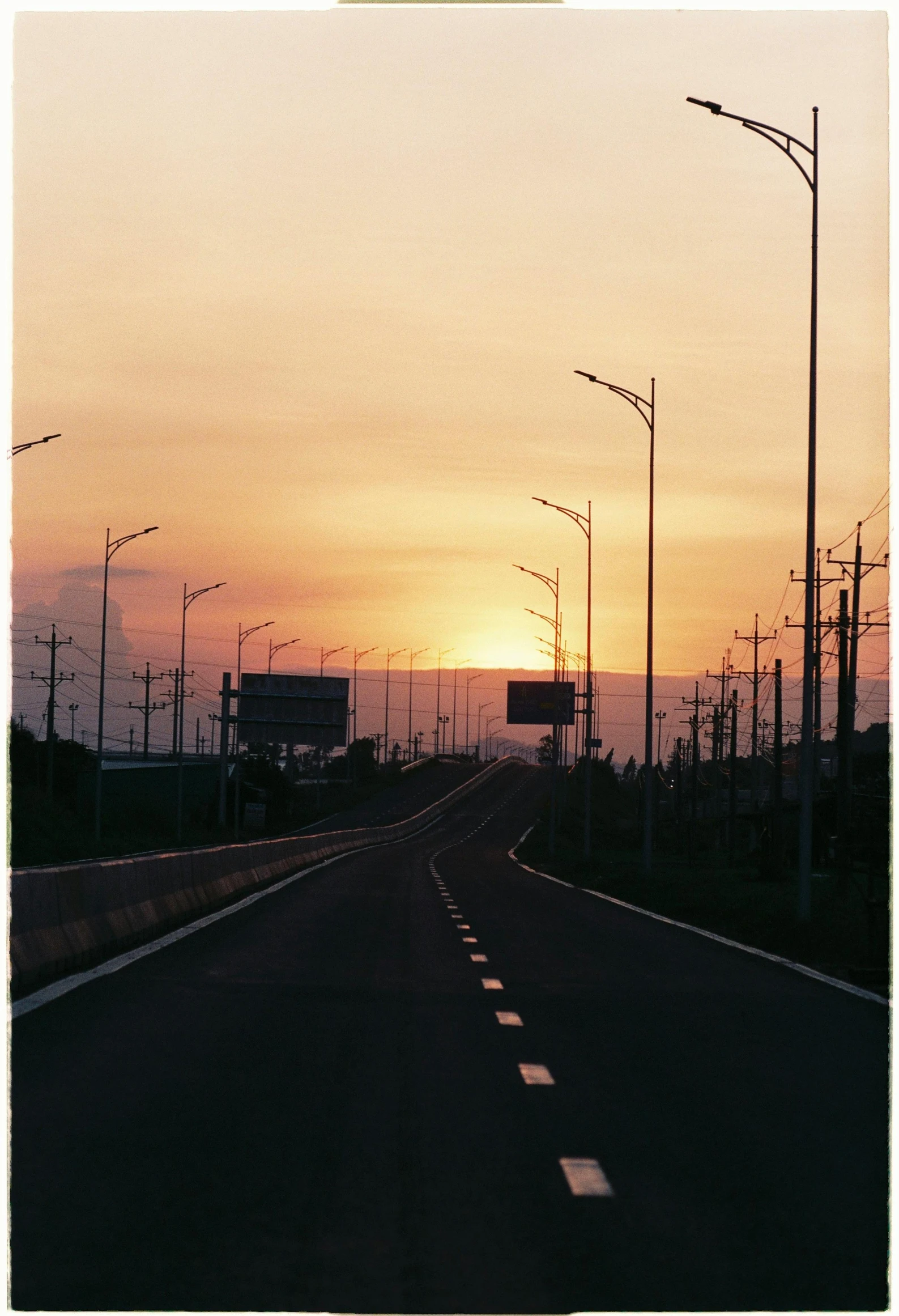 the sun sets on a freeway that leads to the ocean