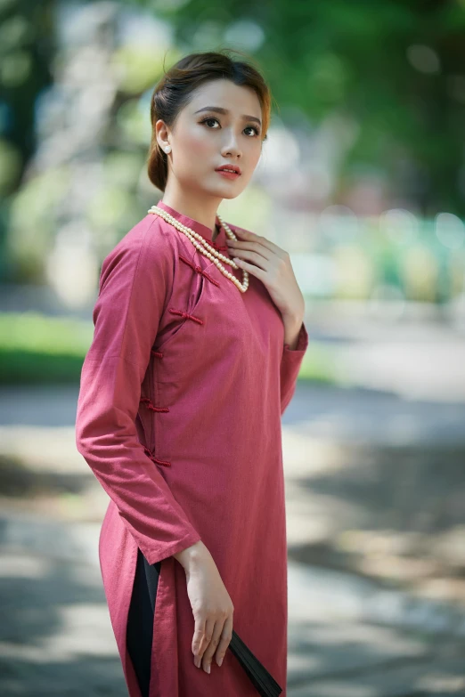 a woman in red shirt standing on street near tree