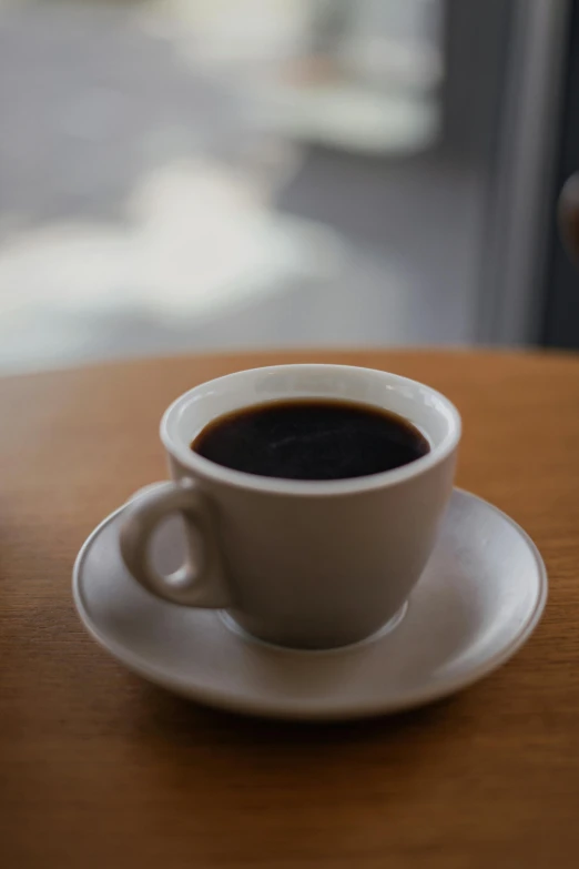 there is a cup of black coffee on a brown table