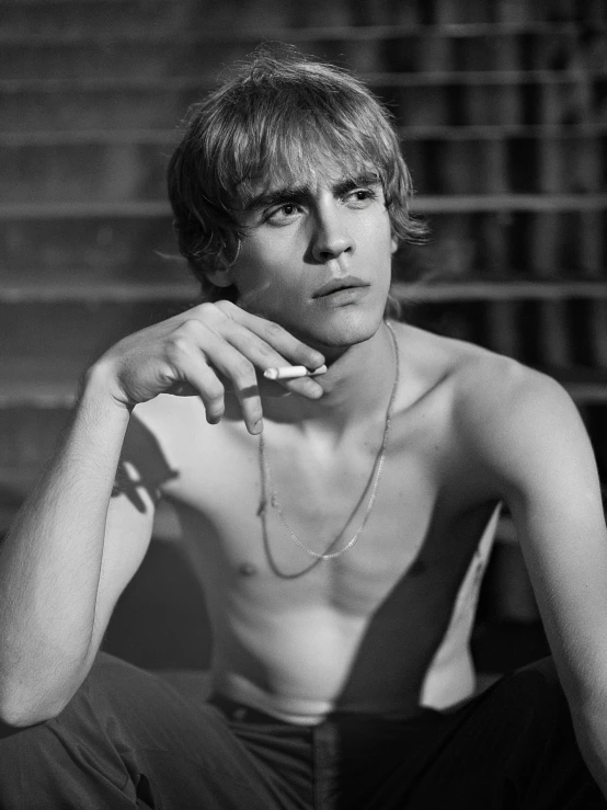 a young man with long blonde hair sitting on some stairs