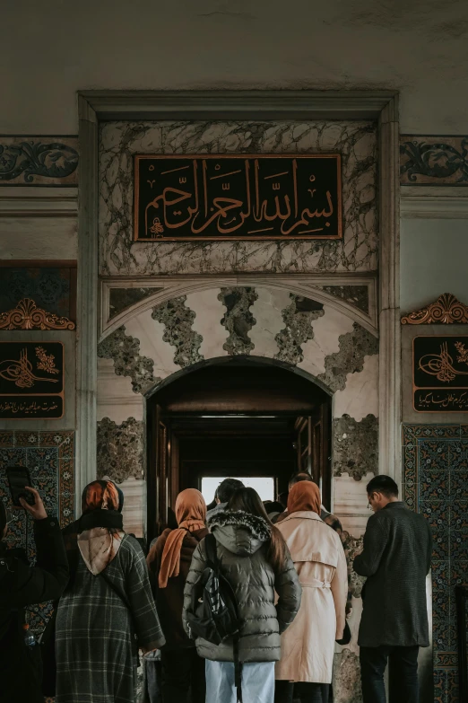 several people standing around in a building with arabic writing above the doors