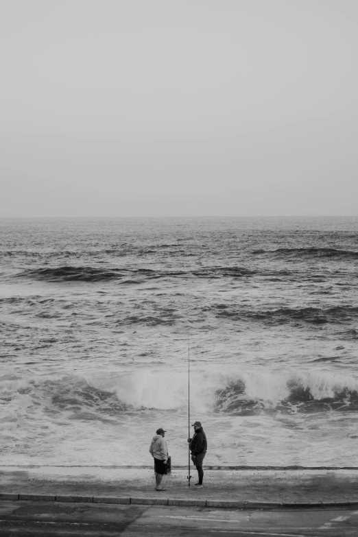 two people standing on the beach next to a body of water