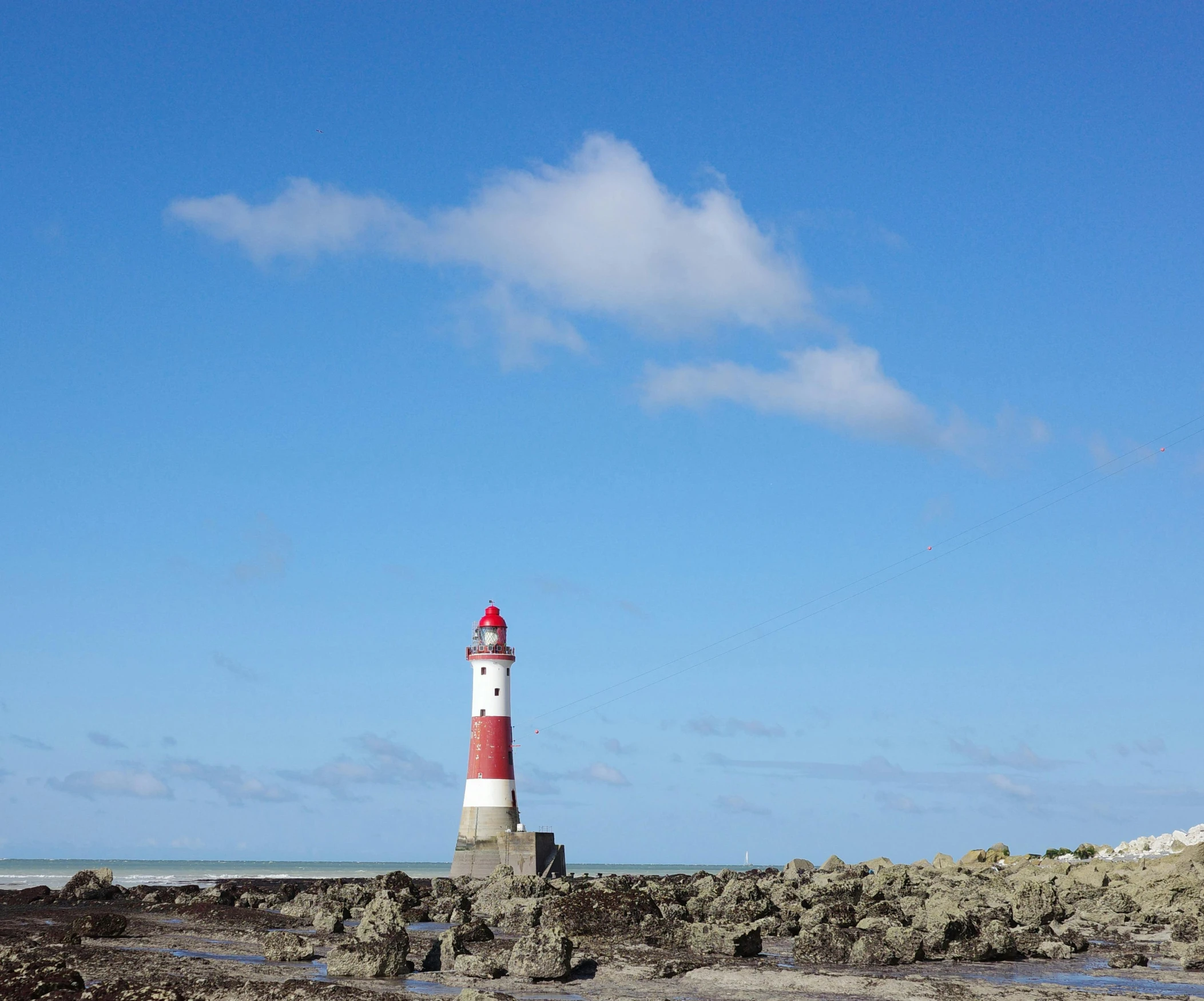 a lighthouse sits in a rocky area on the beach