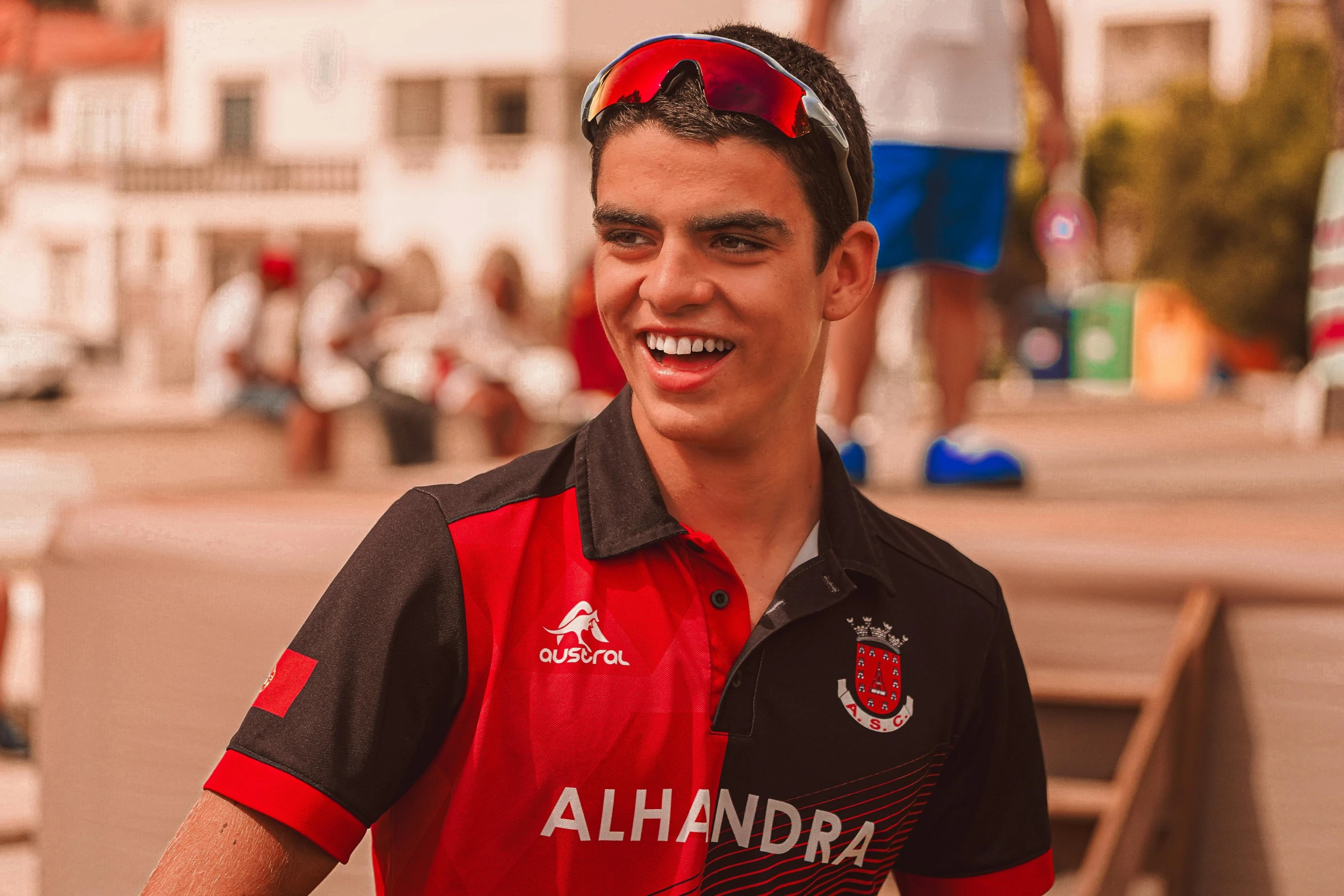 a smiling male soccer player wearing sunglasses and a black shirt