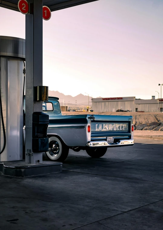 an old style truck at a gas station