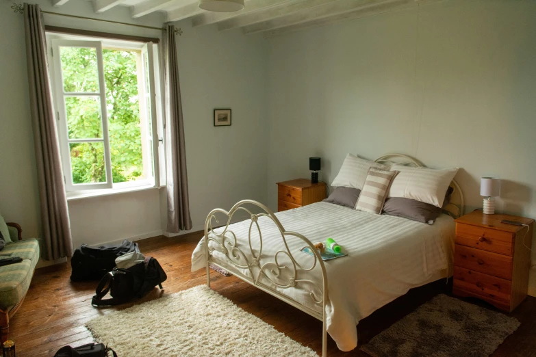 a small bedroom with large windows and a bed with a white bedspread