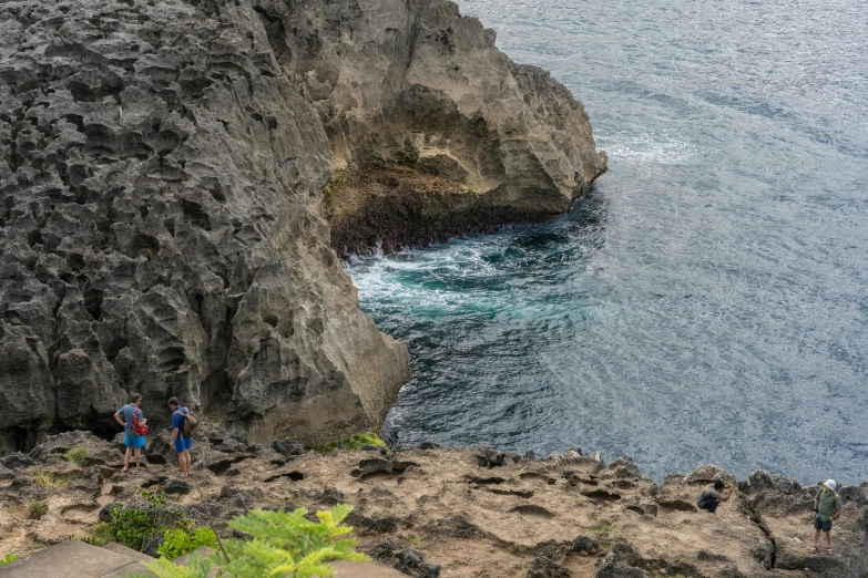 two people are hiking along the rocky cliff overlooking the ocean