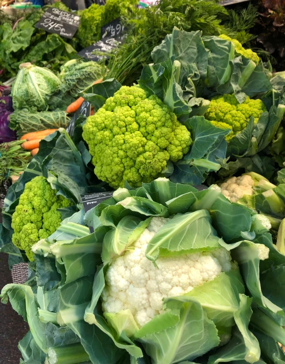 a pile of green vegetables with some carrots in it