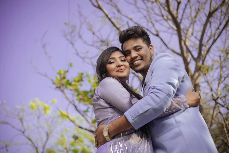 a young woman hugging a man with green leaves in the background