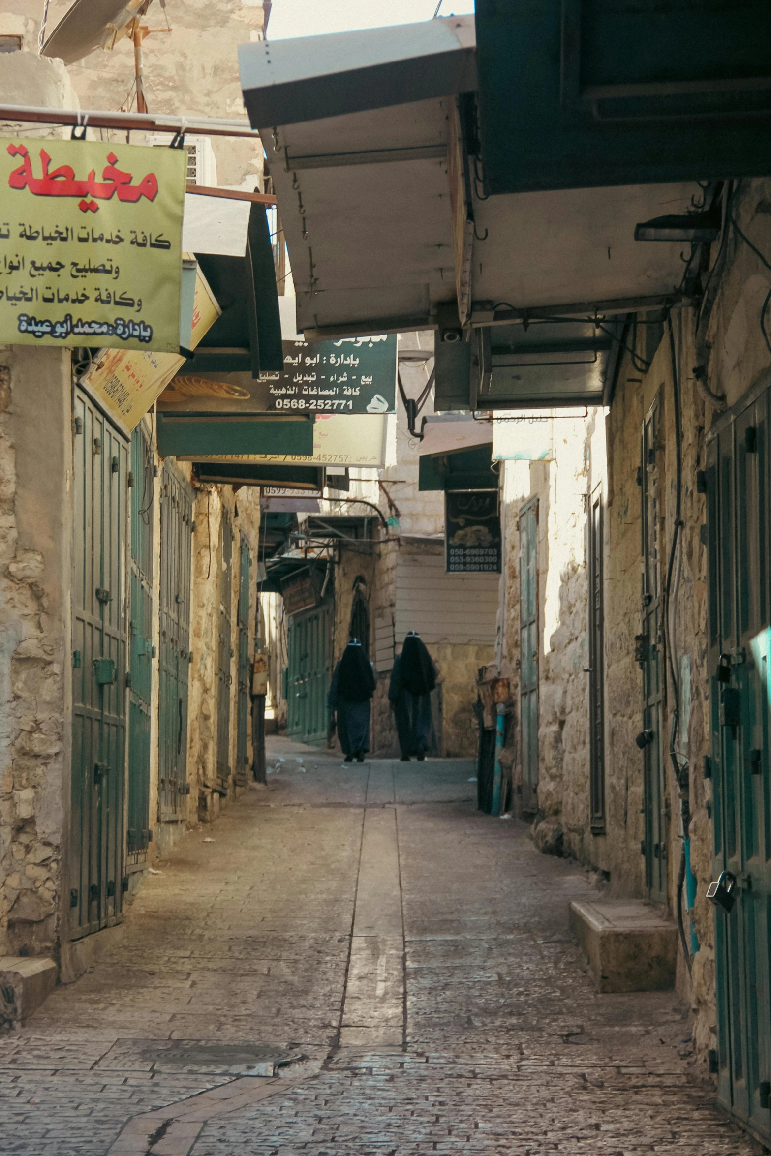 two people walking through a street lined with stone buildings