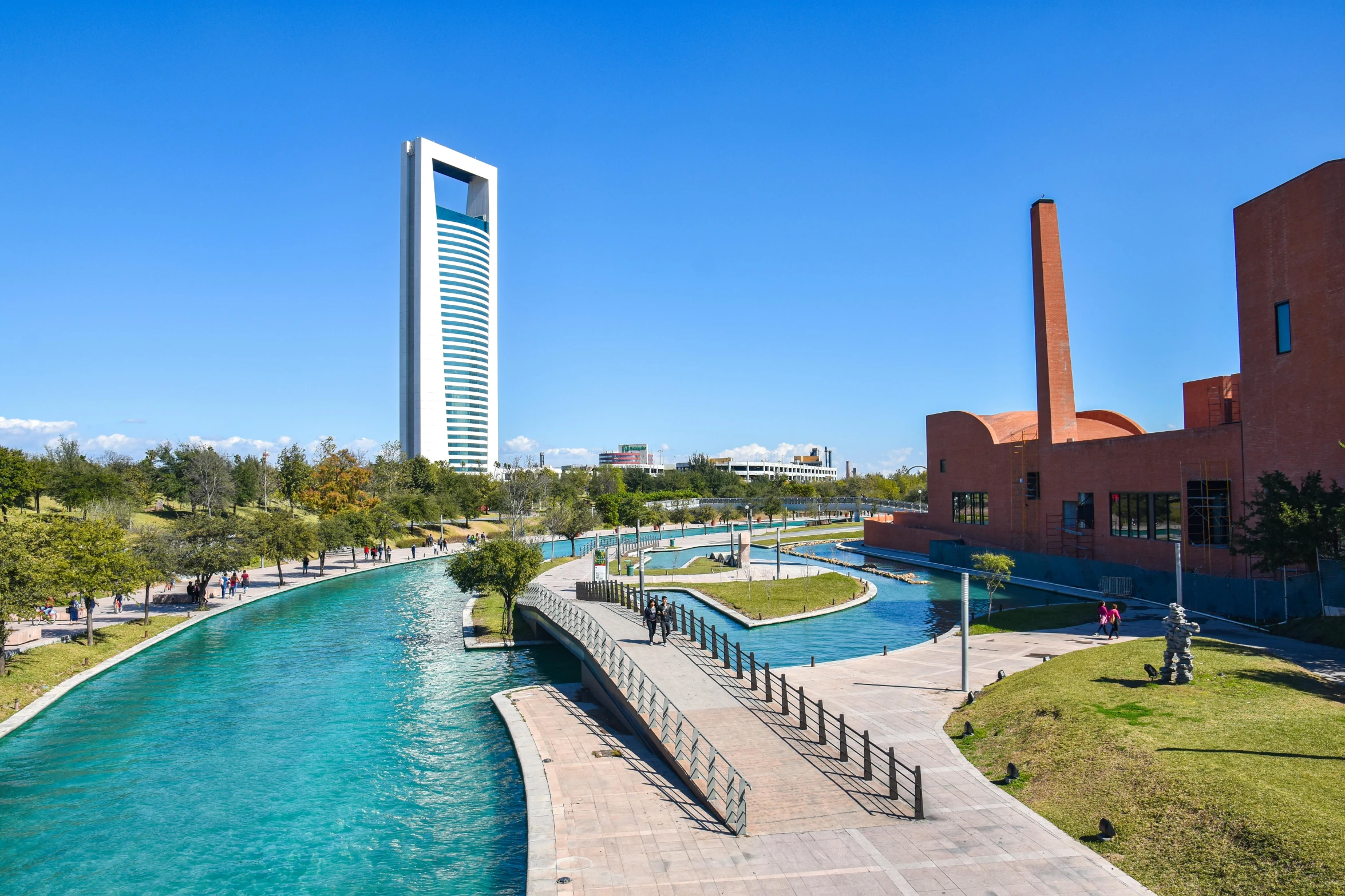 people are walking near a blue river with green water