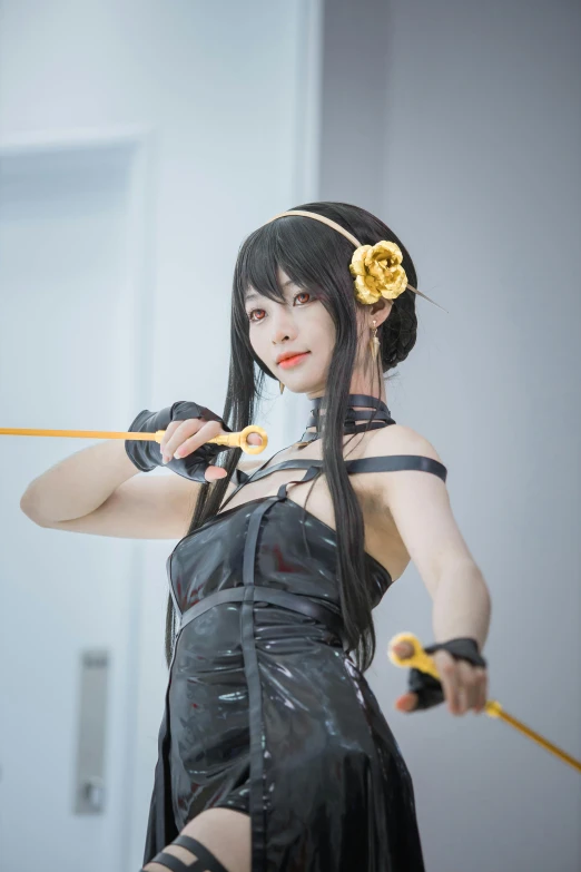 a woman holding an o - rope, dressed in black rubber with flower attached to it