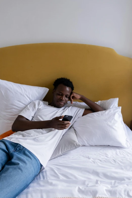 the man is on his cellphone lying in bed