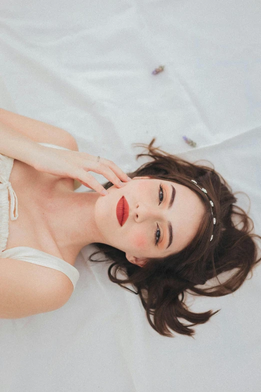 a beautiful young woman with black hair laying on top of a bed