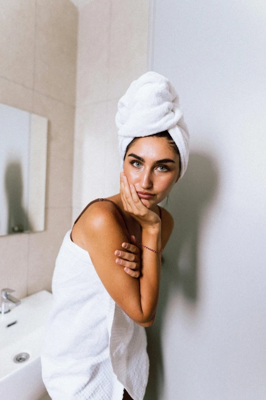 a beautiful woman in a towel is standing by the mirror