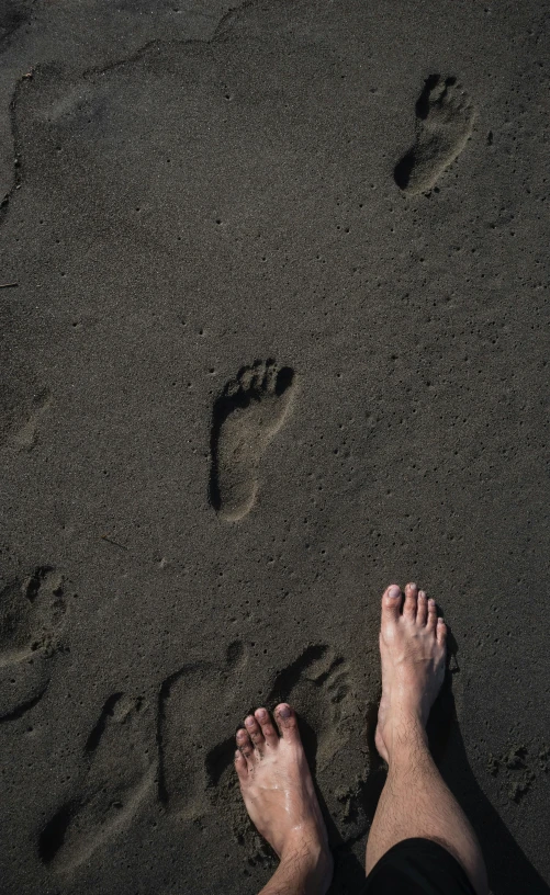 a person standing on a beach with their feet in the sand