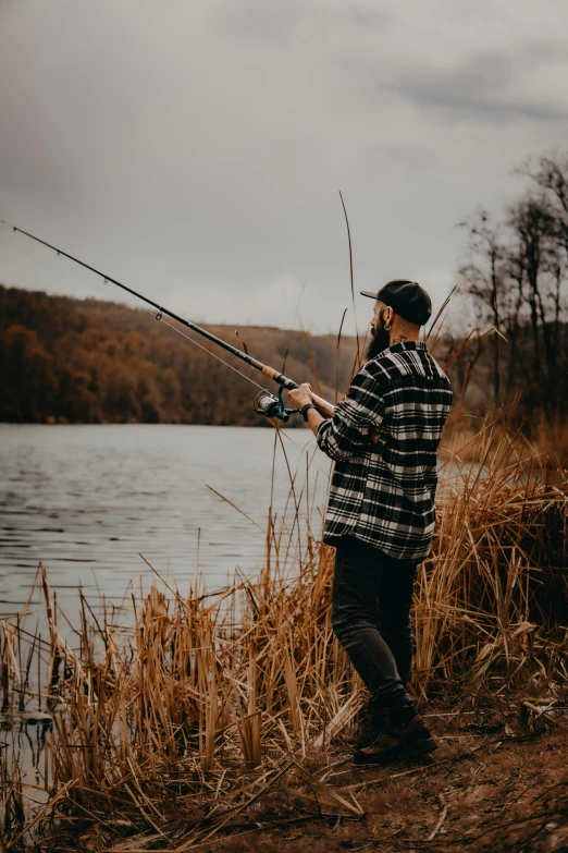 a man standing by the water, holding a fish