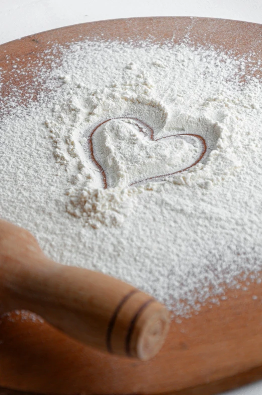 a heart shaped cookie dough on top of a wooden board