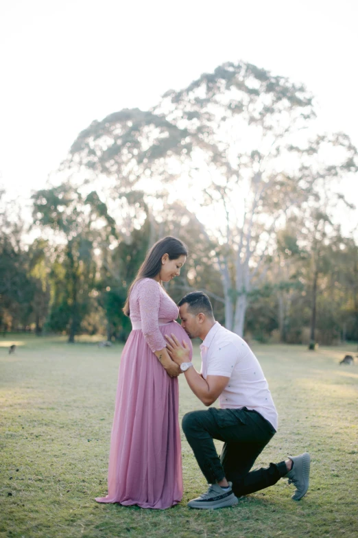 a man kneeling down with his arm around a woman's waist