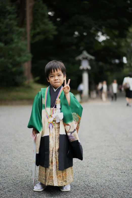 a little boy in traditional clothing waves to the camera