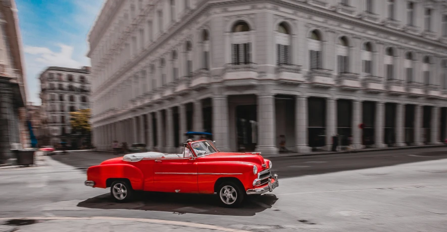 an old classic car that is red and parked in the street