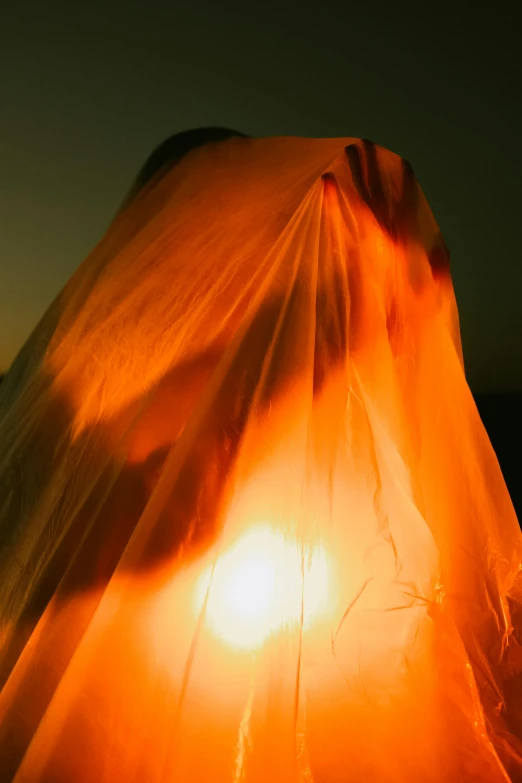 an orange cloth covering a white lamp that is on