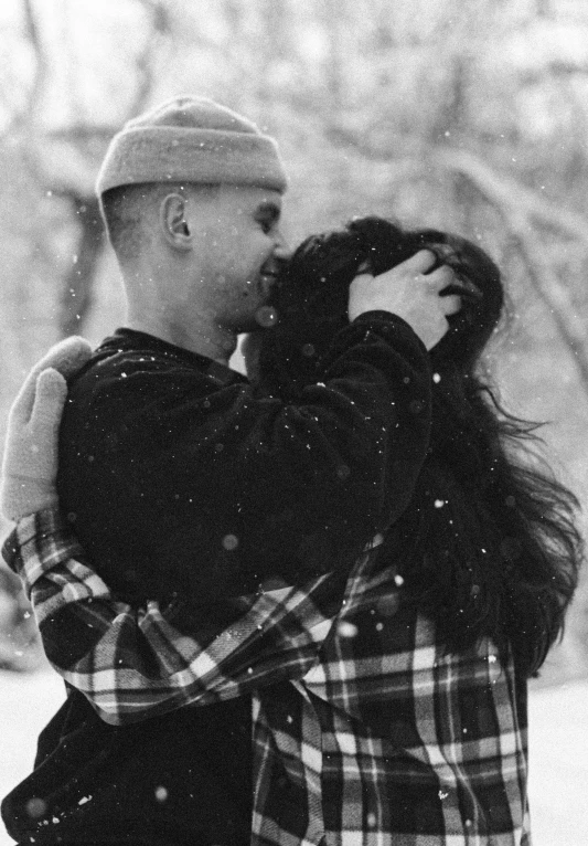 man holding a young woman, in a snow covered field