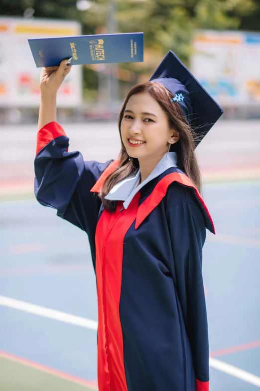 a young woman with a blue diploma in the air