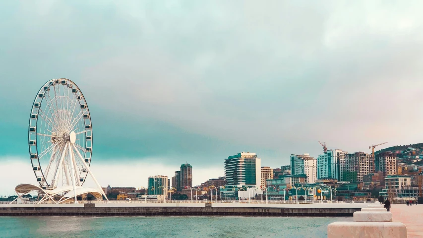 a ferris wheel is near the ocean and the city