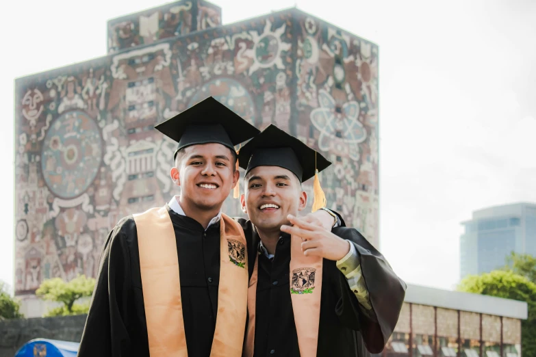 two young graduates smiling and posing in front of some buildings