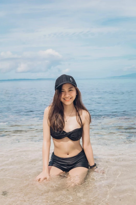 a woman is sitting in the shallow water on the beach