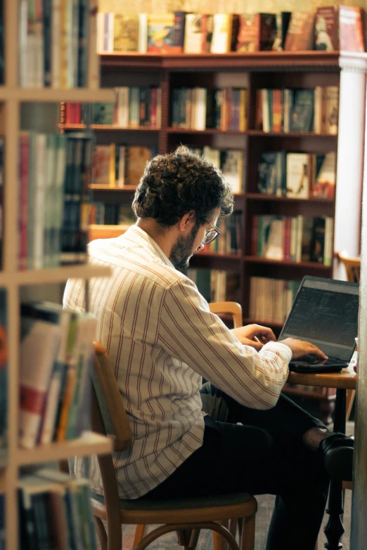 man with glasses working on laptop in liry