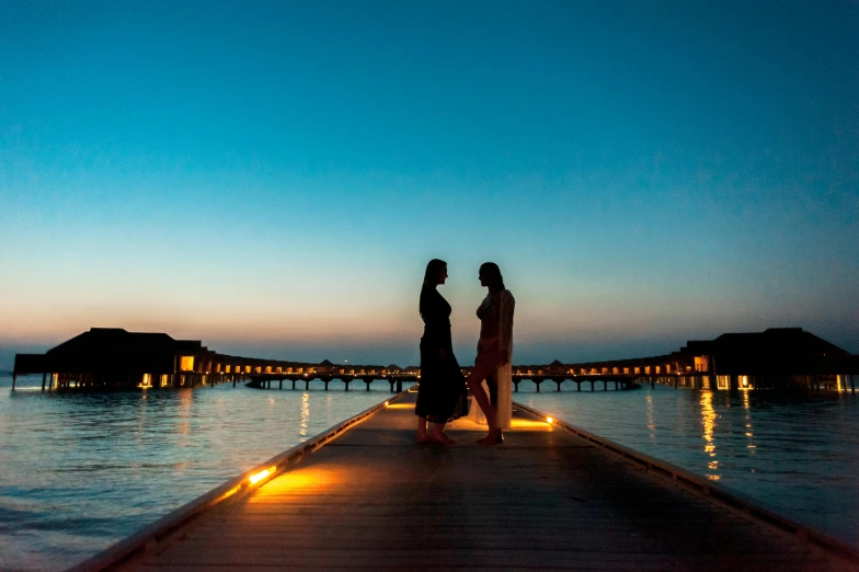 two people walking down a pier over water