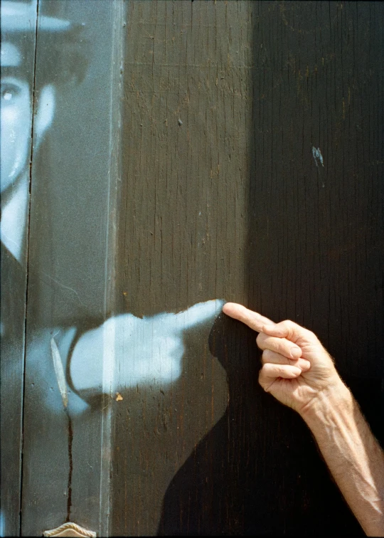 someone pointing to a shadow of a man on a window