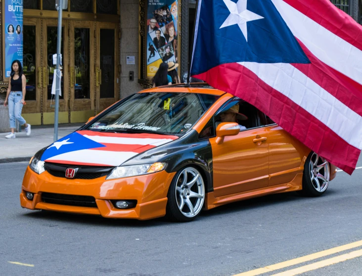a car with an american flag on the roof driving down a street