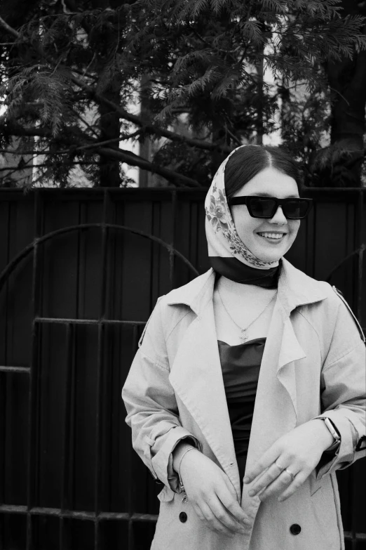 woman standing in front of gate with sunglasses on