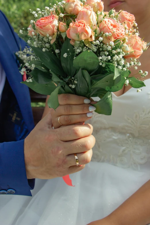 a bride holding a bouquet with orange roses in her hand