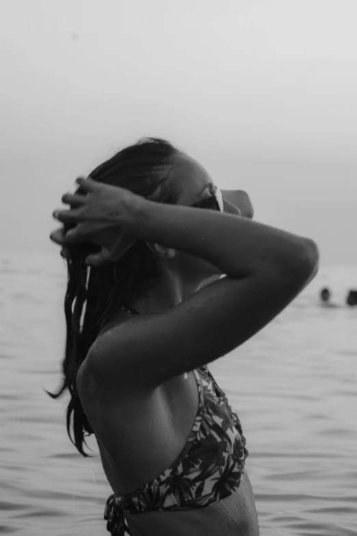 a woman wearing a bathing suit standing next to a body of water