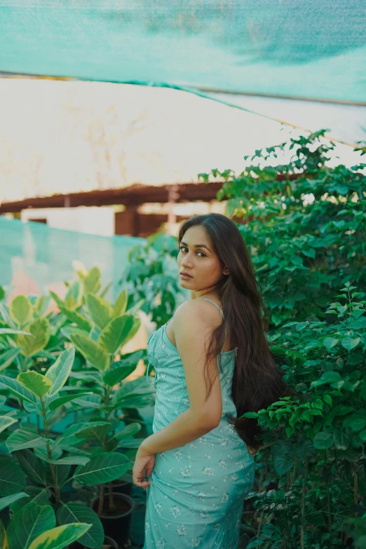 a beautiful young lady posing in front of green bushes