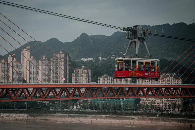 a cable car riding over a bridge in front of city buildings