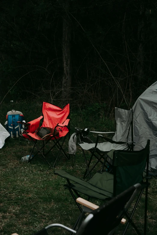 several camping chairs are on a grassy field