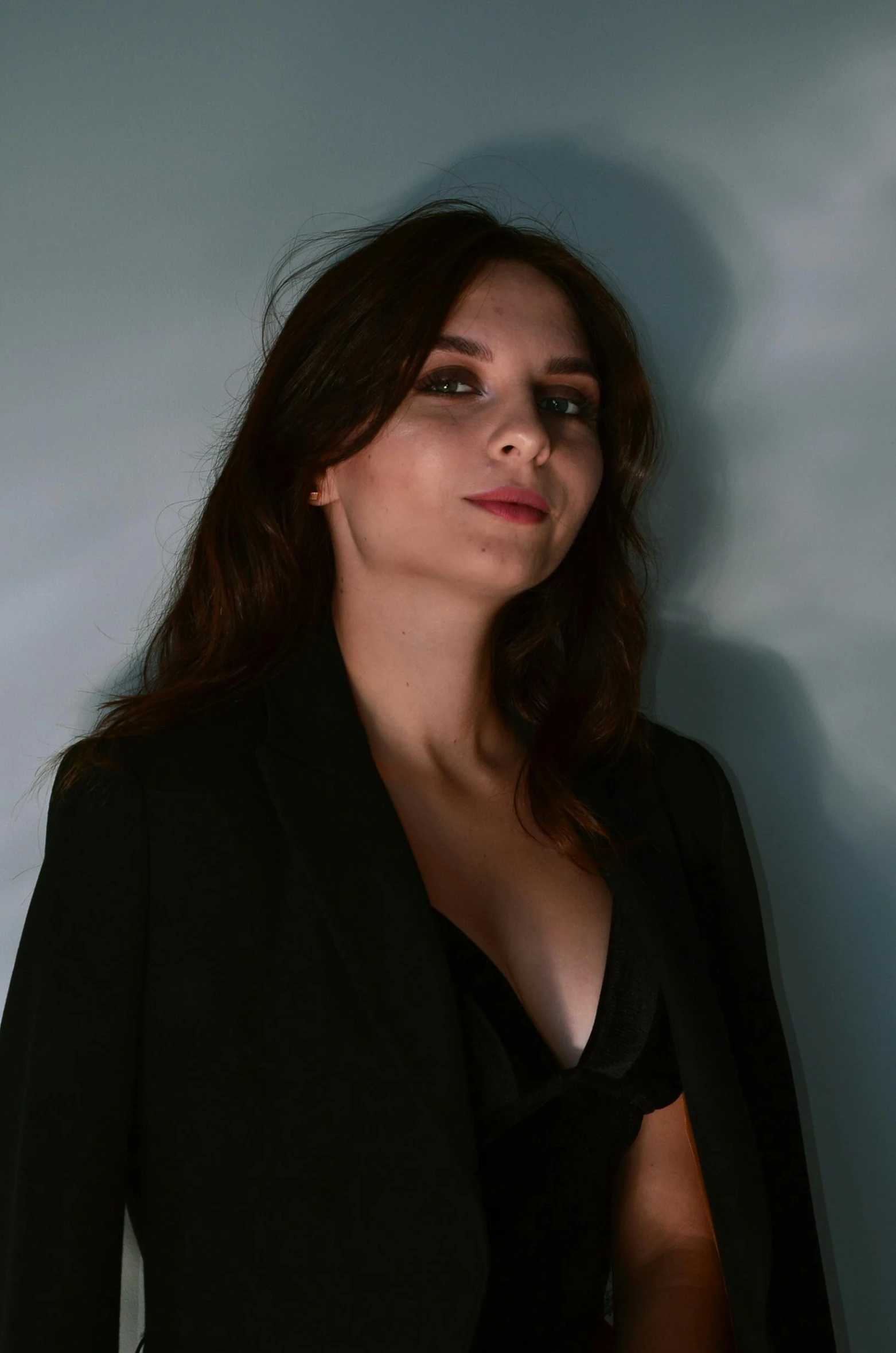 a woman wearing a suit standing in front of a gray background