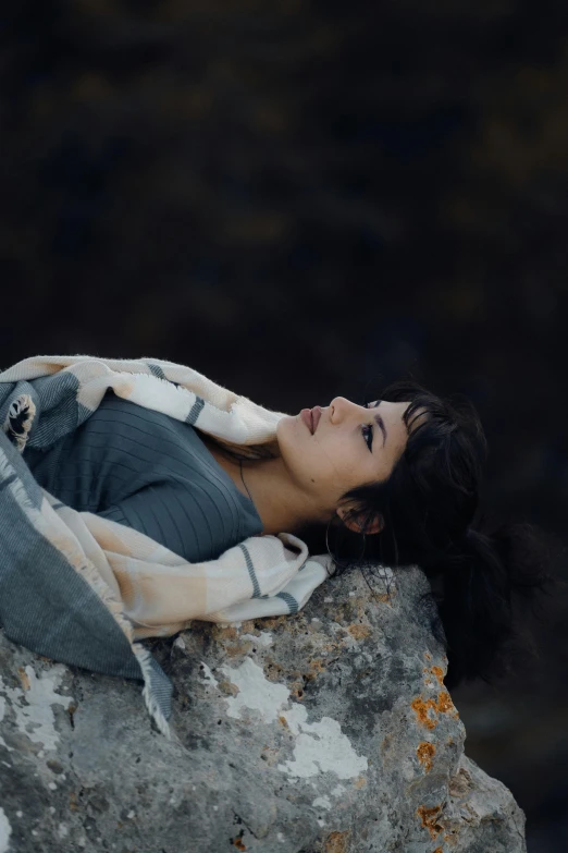 a woman laying on top of a big rock