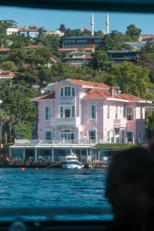 a pink house is sitting next to the water